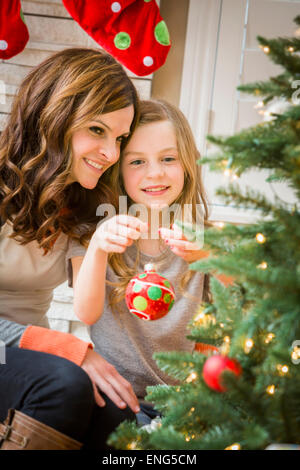 Caucasian mother and daughter decorating Christmas tree Stock Photo