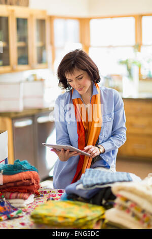Hispanic business owner taking inventory with digital tablet in home office Stock Photo