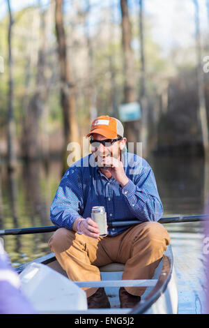 Caucasian man drinking beer in canoe on river Stock Photo
