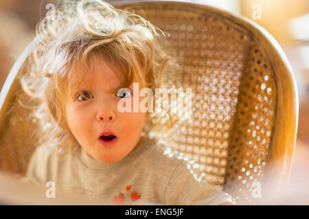 Caucasian baby boy gasping in wicker chair Stock Photo