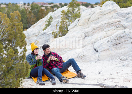 Couple sharing coffee on rock formations Stock Photo