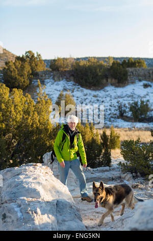 Older man and dog standing on remote rock formations Stock Photo