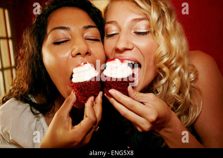 Close up of women eating red velvet cupcakes