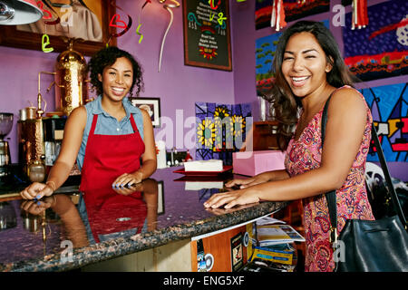 Barista and customer smiling in coffee shop Stock Photo