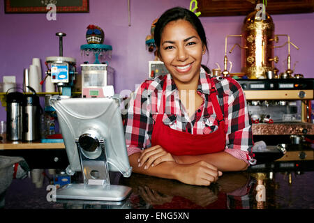 Hispanic barista smiling in coffee shop Stock Photo