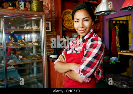 Hispanic waitress smiling in bakery Stock Photo