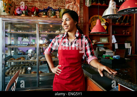 Hispanic waitress smiling in bakery Stock Photo
