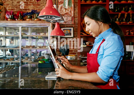 Hispanic cashier using digital tablet register in bakery Stock Photo