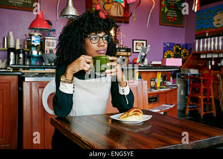 Mixed race woman drinking coffee in cafe Stock Photo