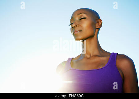 African American woman smiling in sunburst under blue sky Stock Photo
