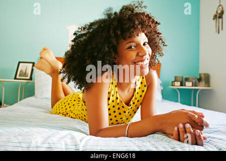 Smiling mixed race woman laying on bed Stock Photo