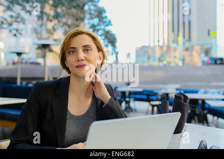 Caucasian businesswoman working at sidewalk cafe Stock Photo