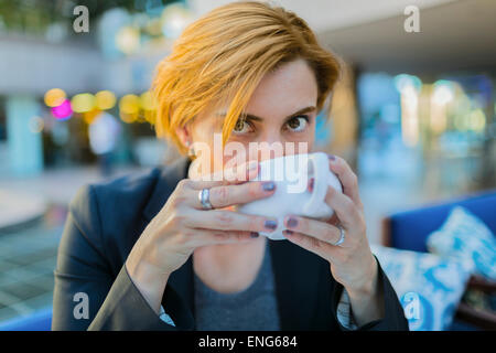 Caucasian businesswoman drinking coffee at sidewalk cafe Stock Photo