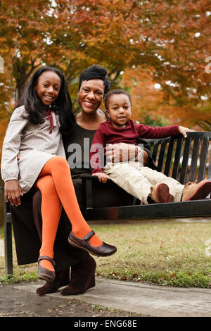 African American mother and children sitting on park bench