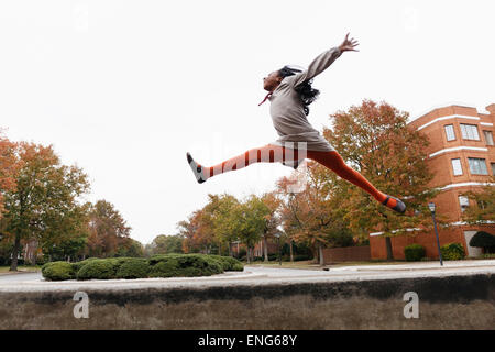 African American girl jumping for joy on suburban street