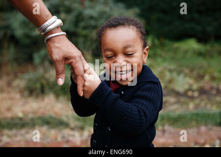 African American boy holding hand of mother in park Stock Photo