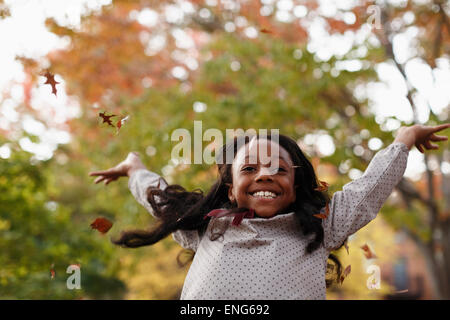 Low angle view of African American girl playing in autumn leaves Stock Photo