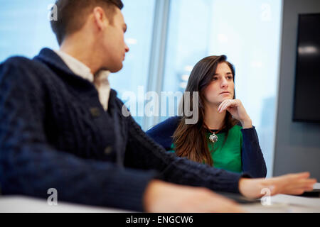 A man and woman seated at a meeting in an office. Stock Photo