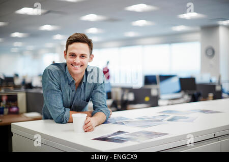 A man smiling and leaning forward on his desk. Stock Photo