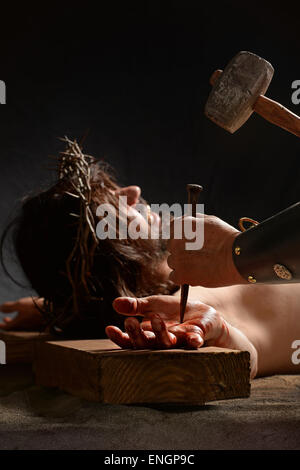 Jesus hand being nailed to the cross by Roman soldier Stock Photo