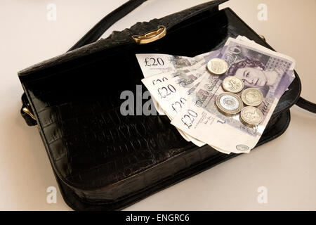 British Pound Notes£20 and 1 and 2 pound coins on Black Crocodile skin Handbag, gilt clasp Stock Photo