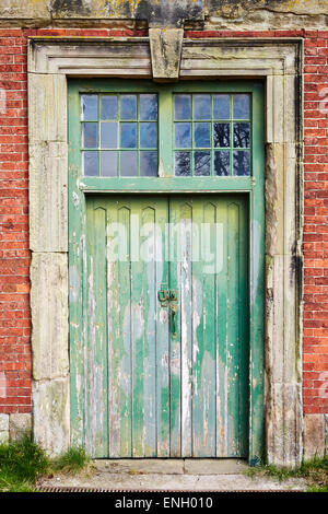 Green wooden door with stone surround in the old stable block at Calke Abbey, Derbyshire, England, UK. Stock Photo