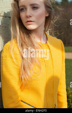 portrait of young woman in yellow jacket with blonde hair Stock Photo