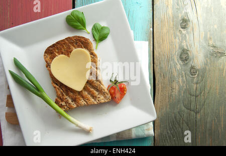 Heart shape slice of cheese on toasted whole grain bread Stock Photo