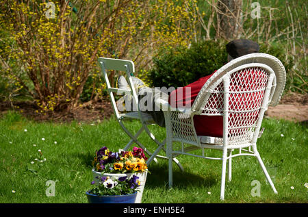 Man pensioner - senior sitting on chair in garden relaxing Stock Photo