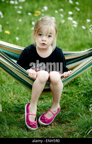 Portrait of Little Child blond girl lying and resting in a hammock, garden yard, summer Stock Photo