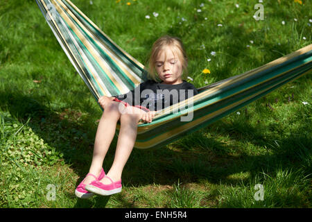 Portrait of Little Child blond girl lying and resting in a hammock, garden yard, summer Stock Photo