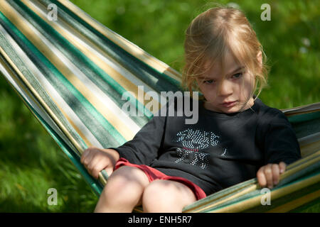 Portrait of Little Child blond girl lying and resting in a hammock, garden yard, summer Stock Photo