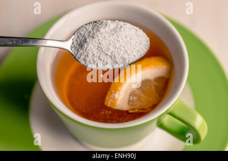 Sweetener is poured from a spoon in a cup of tea Stock Photo