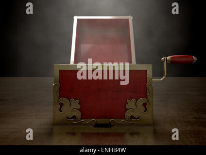 An ornate antique open jack-in-the-box mad of red wood and gold trimmings on a dark studio background under a spotlight Stock Photo