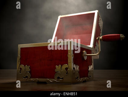 An ornate antique open jack-in-the-box mad of red wood and gold trimmings on a dark studio background under a spotlight Stock Photo