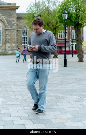 Young man walking whilst using mobile phone Stock Photo
