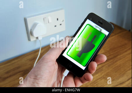 iphone 5 mobile phone on charge in a UK plug socket. Stock Photo