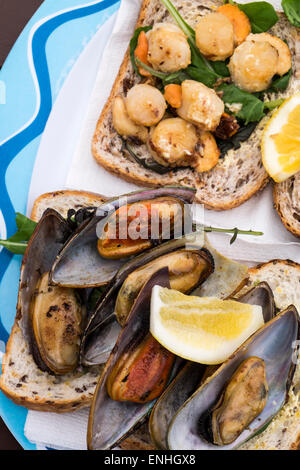 Barbecued scallops and green lipped mussels on bread at an outdoor food shack on the beach at Kaikoura, New Zealand Stock Photo