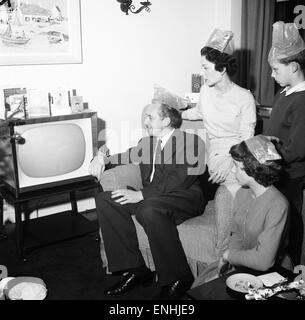 Tv presenter Hughie Green seen here at home at Christmas time with his family. Left to right Hughie Green, wife Claire, daughter Linda and son Christopher. The bush baby sitting on Hughie's arm was a Christmas present to his son . 27th December 1957 Stock Photo