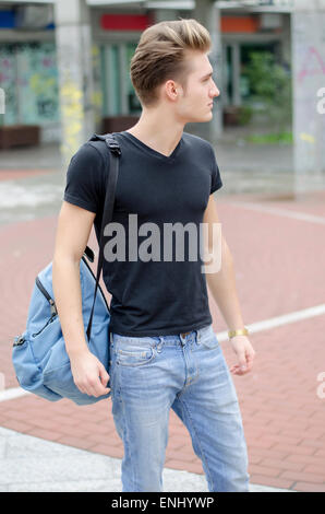 Attractive young man with backpack standing outside Stock Photo