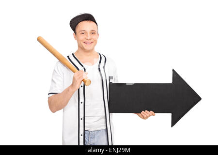 Young man in a baseball shirt holding a baseball bat and an arrow pointing right isolated on white background Stock Photo