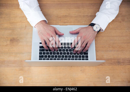 Closeup image of a businessman hands using laptop on wooden table Stock Photo