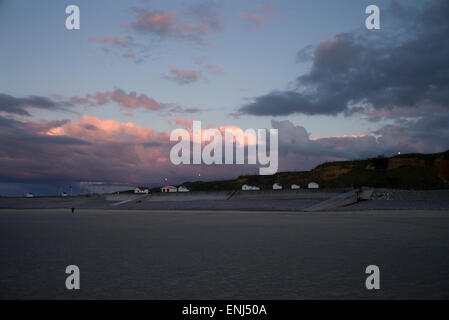 Solitary figure on empty beach, beach huts, evening light, Normandy, France Stock Photo