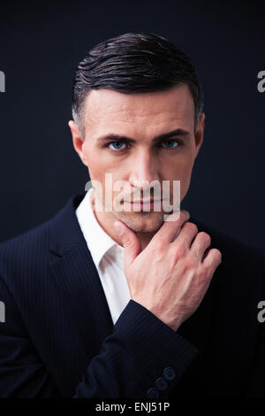 Handsome businessman in formal wear looking at camera over black background Stock Photo