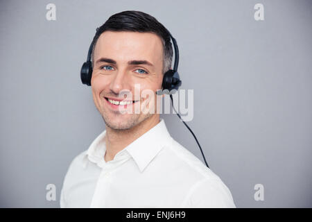 Smiling young male operator in headphones looking at camera over gray background Stock Photo