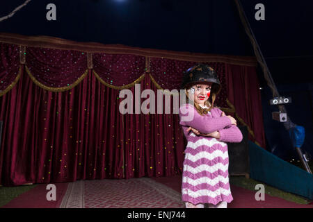 Tough Looking Girl Wearing Combat Helmet and Striped Dress Standing Confidently with Arms Crossed on Stage with Red Curtain Stock Photo