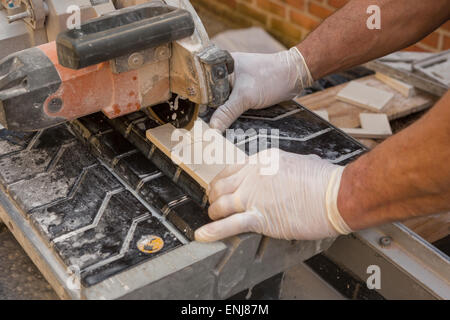 ARLINGTON, VIRGINIA, USA - Worker wearing latex gloves cuts ceramic tiles with a wet tile saw. Stock Photo