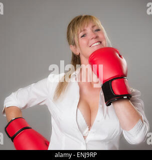 Female boxer wearing red 10oz boxing gloves. Taking a punch to the face. Stock Photo