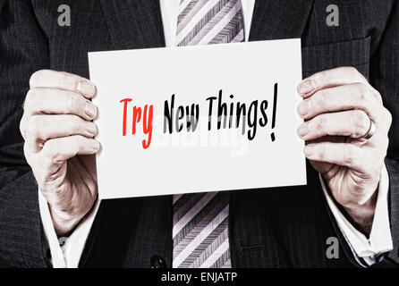 A businessman holding a business card with the words, Try New Things, written on it. Stock Photo