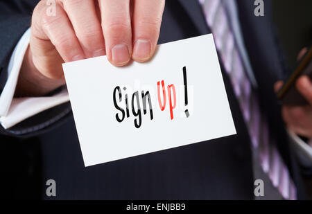A businessman holding a business card with the words, Sign Up, written on it. Stock Photo